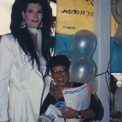 Unknown man dressed as a woman standing with a woman.