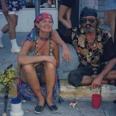 Unknown people sitting on the sidewalk.