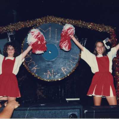 Unknown girls dressed up as cheerleaders on a float.