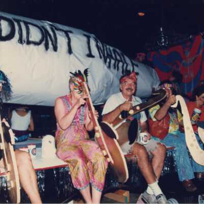 Unknown people dressed up on a float holding fake instruments.