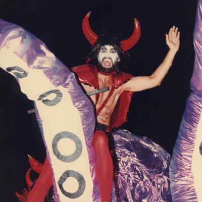 Unknown man dressed up as a devil sitting on top of a float.