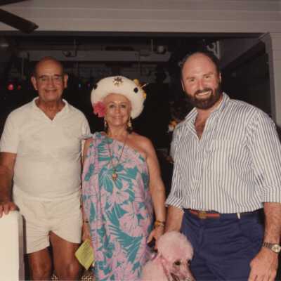 Unknown people standing with a pink poodle.