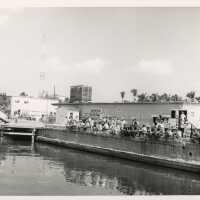 A group of unknown people sitting on a pier