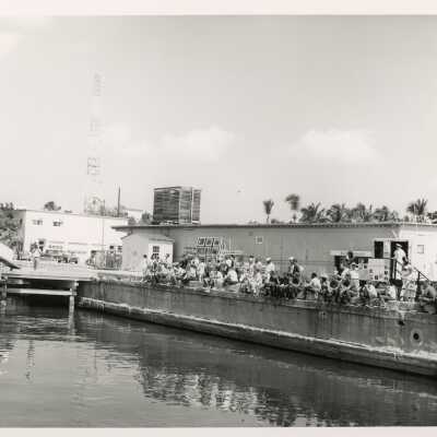 A group of unknown people sitting on a pier