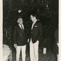 2 Unknown men standing outside at a party talking