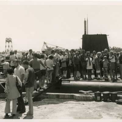 A big crowd of unknown people standing near a ship