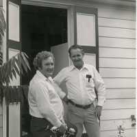 2 Unknown men standing outside next to a house/office