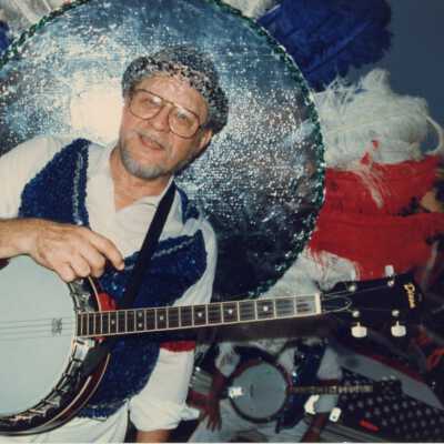 Unknown man dressed up holding some sort of instrument.