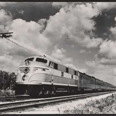 An airplane flying near a Florida East Coast train
