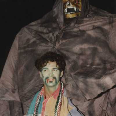 Unknown man dressed up standing under a monster.