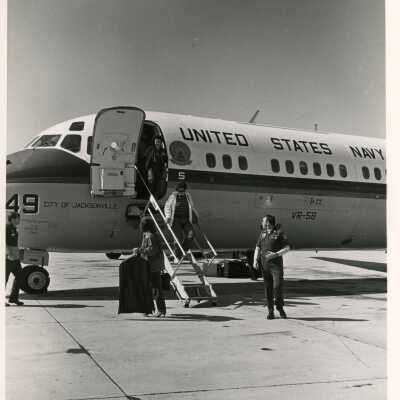 Unknown people coming off of a USN plane