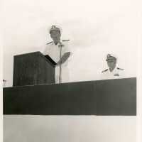 2 Men in uniform talking at the podium