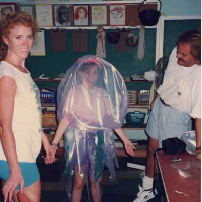 Unknown people in a classroom, a young girl is dressed up.