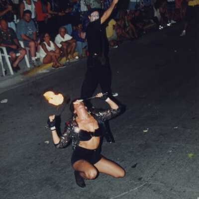 Unknown people dressed up playing with fire in the street.