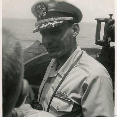 An unknown man in uniform in a ship holding binoculars