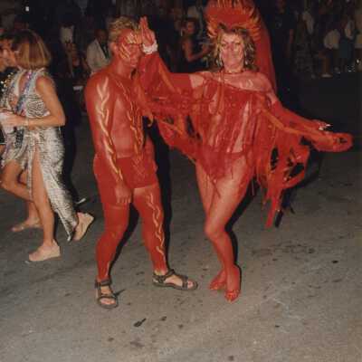 Two unknown people dressed up walking in the street for the parade.