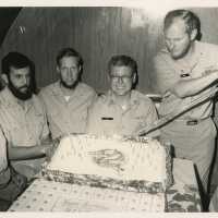 A group of unknown men in uniform with a cake