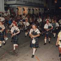 A pipe band playing while walking down the street in the parade.