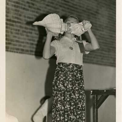 A child holding 2 shells standing on a stage, maybe during a contest