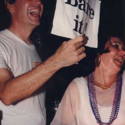 Unknown man and woman, man is holding a sign that reads Bare it.