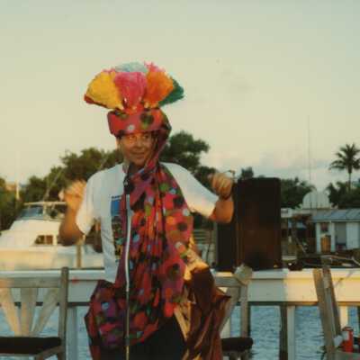 An unknown man dressed up talking into a microphone standing near the water.