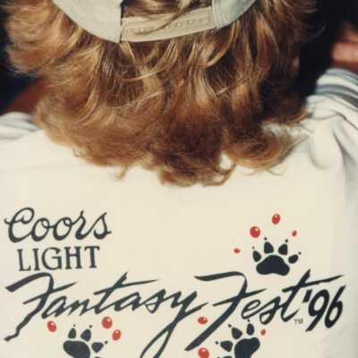 An unknown man wearing a Coors light Fantasy Fest Parade shirt and Key West hat.
