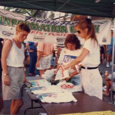 Unknown woman at a booth looking at Fantasy Fest T shirts.