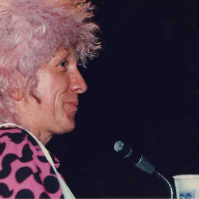 Unknown man dressed up standing next to a microphone.