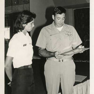 Man in uniform talking to a woman about an award