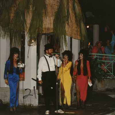 Unknown people dressed up on a stage singing.