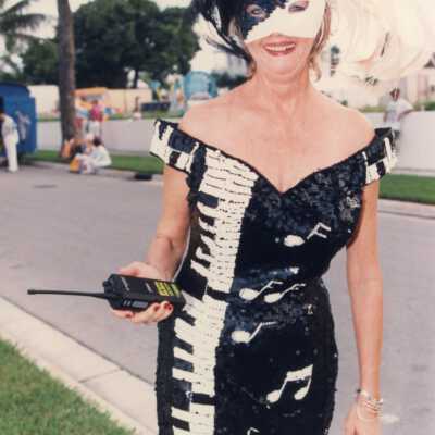 Unknown woman dressed up in a dress that looks like a piano, holding a walkie-talkie.