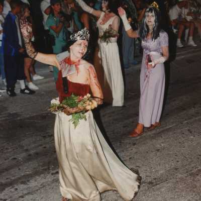Three unknown woman dressed up walking in the street for the parade.