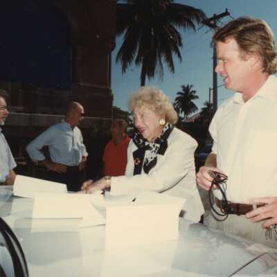 A group of unknown people standing outside of the Custom House with Wilhelmina Harvey.