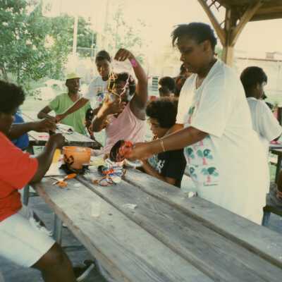 A group of unknown people working outside on a table on crafts.