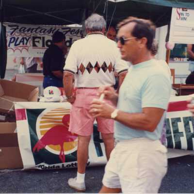 Unknown people walking in front of the Florida street fair both.