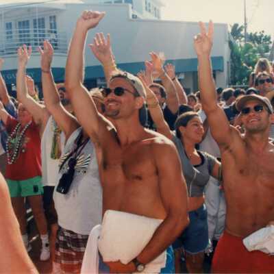 Unknown people in the street looking up and holding an arm up in the air.