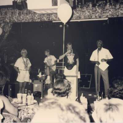 Unknown people on a stage with unknown people sitting at tables.