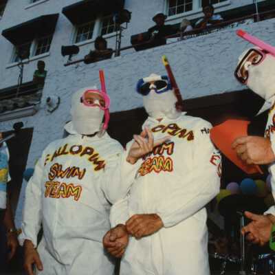 Three unknown men dressed up on a stage.