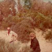 2 Unknown people outside with trees around them