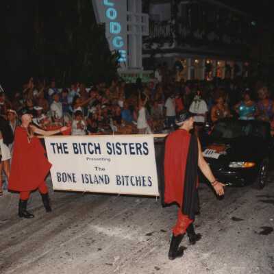 Two unknown people holding a banner that reads The Bitch sisters.