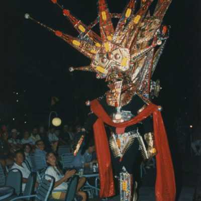 Unknown person dressed up walking down a run way with on lookers.