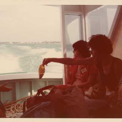 Unknown woman on a boat handing each other objects