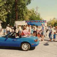 A group of unknown people walking near a booth.