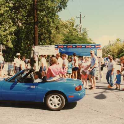 A group of unknown people walking near a booth.