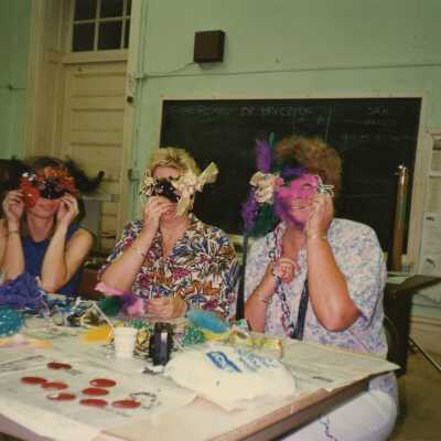 Three unknown woman sitting at a table making face mask.