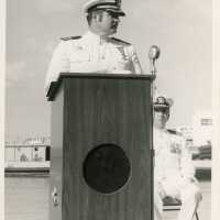 2 Men in uniform, one at the podium