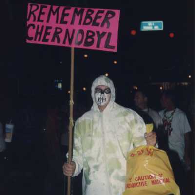 Unknown person dressed up holding a sign that reads remember Chernobyl.