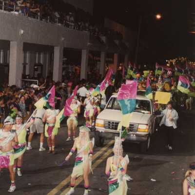 An unknown group of people dressed up walking in the street for the parade.