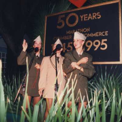 Three unknown woman on a stage.