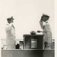 2 Men in uniform saluting each other near a podium